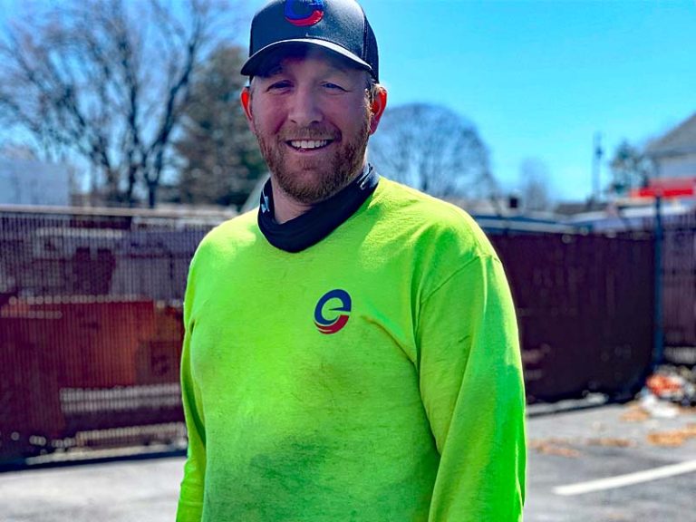 Smiling technician in a neon green Encore shirt and cap standing outdoors